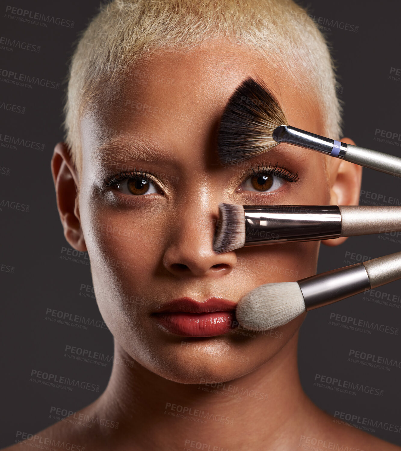 Buy stock photo Woman, portrait and makeup brushes on face for beauty cosmetics, skincare or treatment against a gray studio background. Beautiful female holding cosmetic brushing tools for facial, self care or love