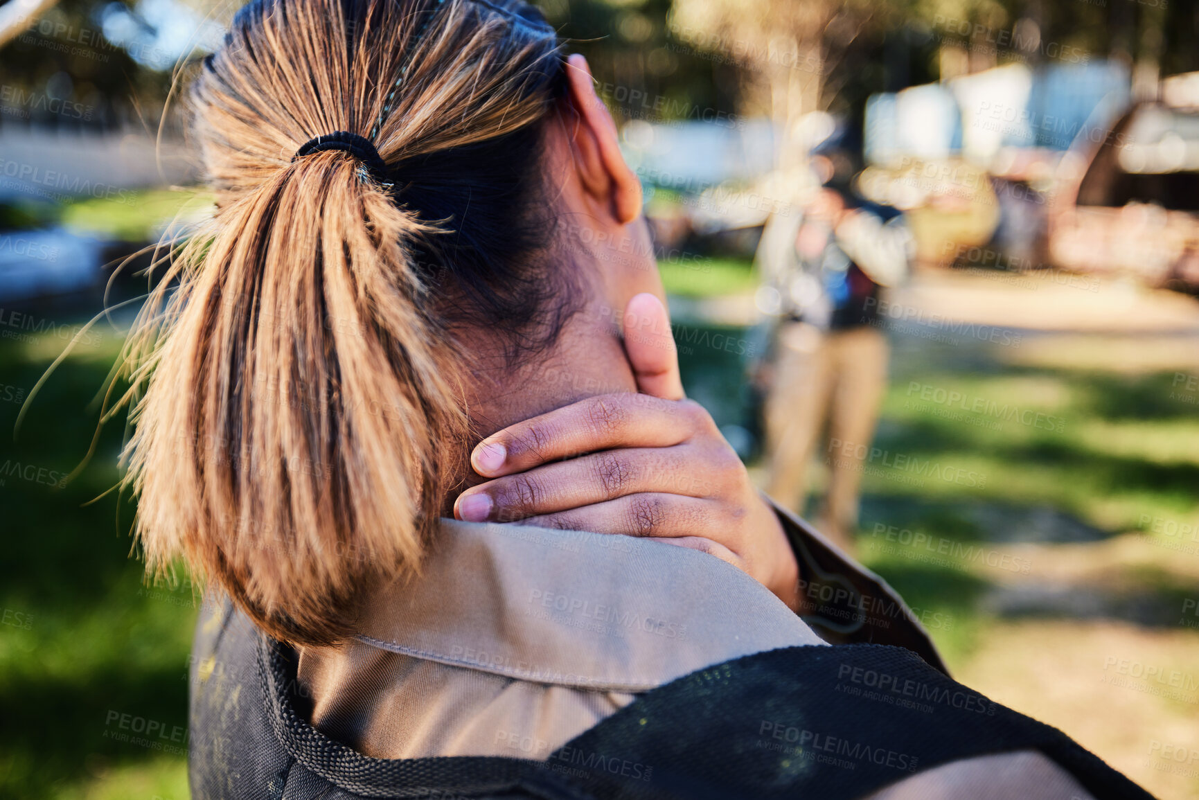 Buy stock photo Closeup, neck pain and hand of woman with injury in paintball, sports and training on blurred background. Rear view, back pain and injured girl with accident during sport, workout or match on a field