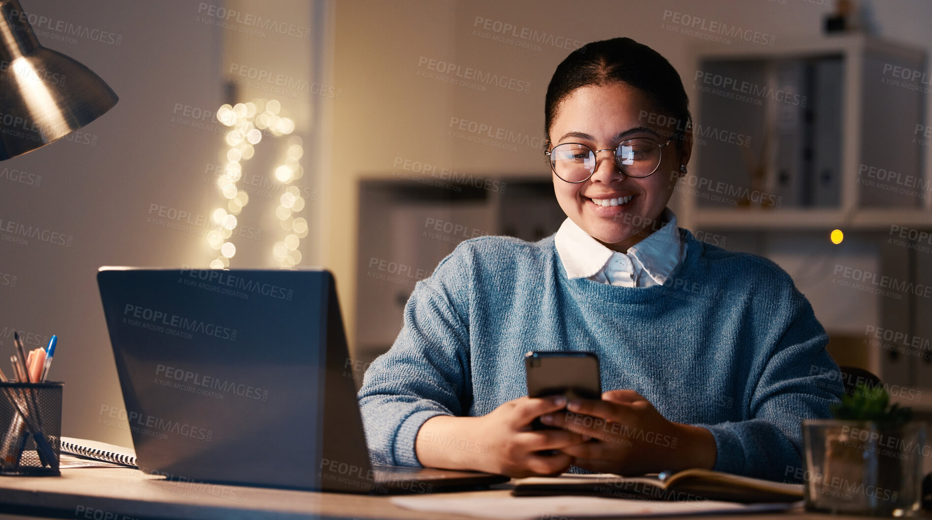 Buy stock photo Woman, phone and student with laptop in home for elearning, project or studying at night. Bokeh, mobile and smile of happy business female, freelancer or remote worker with smartphone for research.