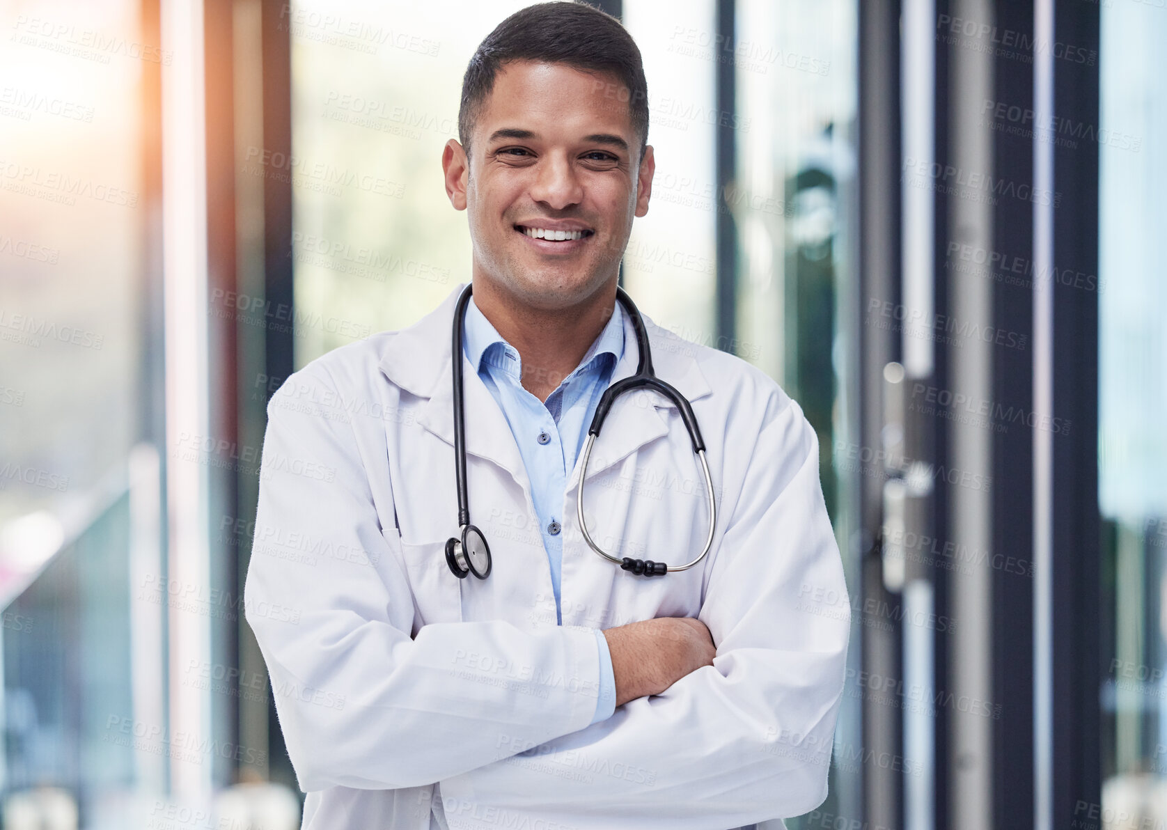 Buy stock photo Portrait, man and happy doctor with arms crossed, stethoscope and confident surgeon in hospital. Proud young healthcare worker smile in lab coat, medical services and surgery trust in wellness clinic