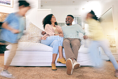 Buy stock photo Children running, happy home and couple on a sofa, talking and relax while bonding in a living room. Blur, kids and content parents on a couch, smile and enjoying weekend indoors with playing and fun