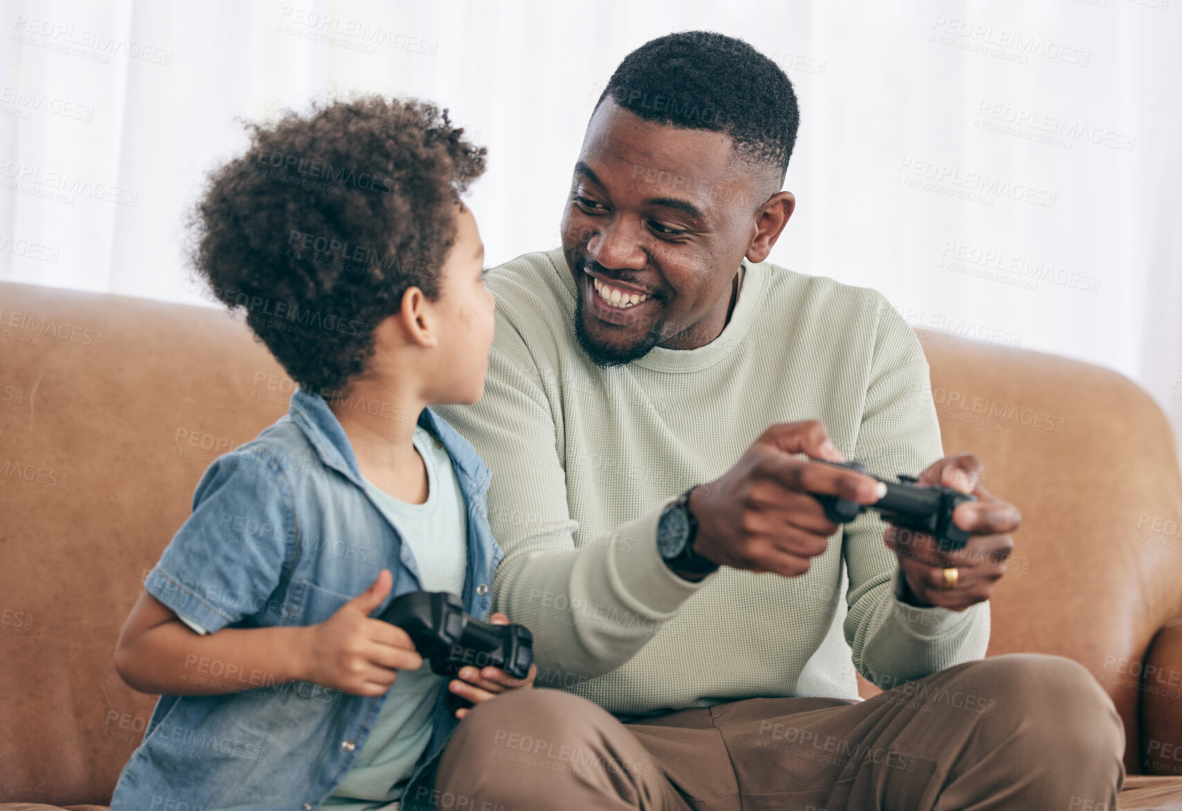 Buy stock photo Black family, father and child playing video games on living room sofa together with controllers at home. Happy African American dad with son with smile enjoying bonding time on console entertainment