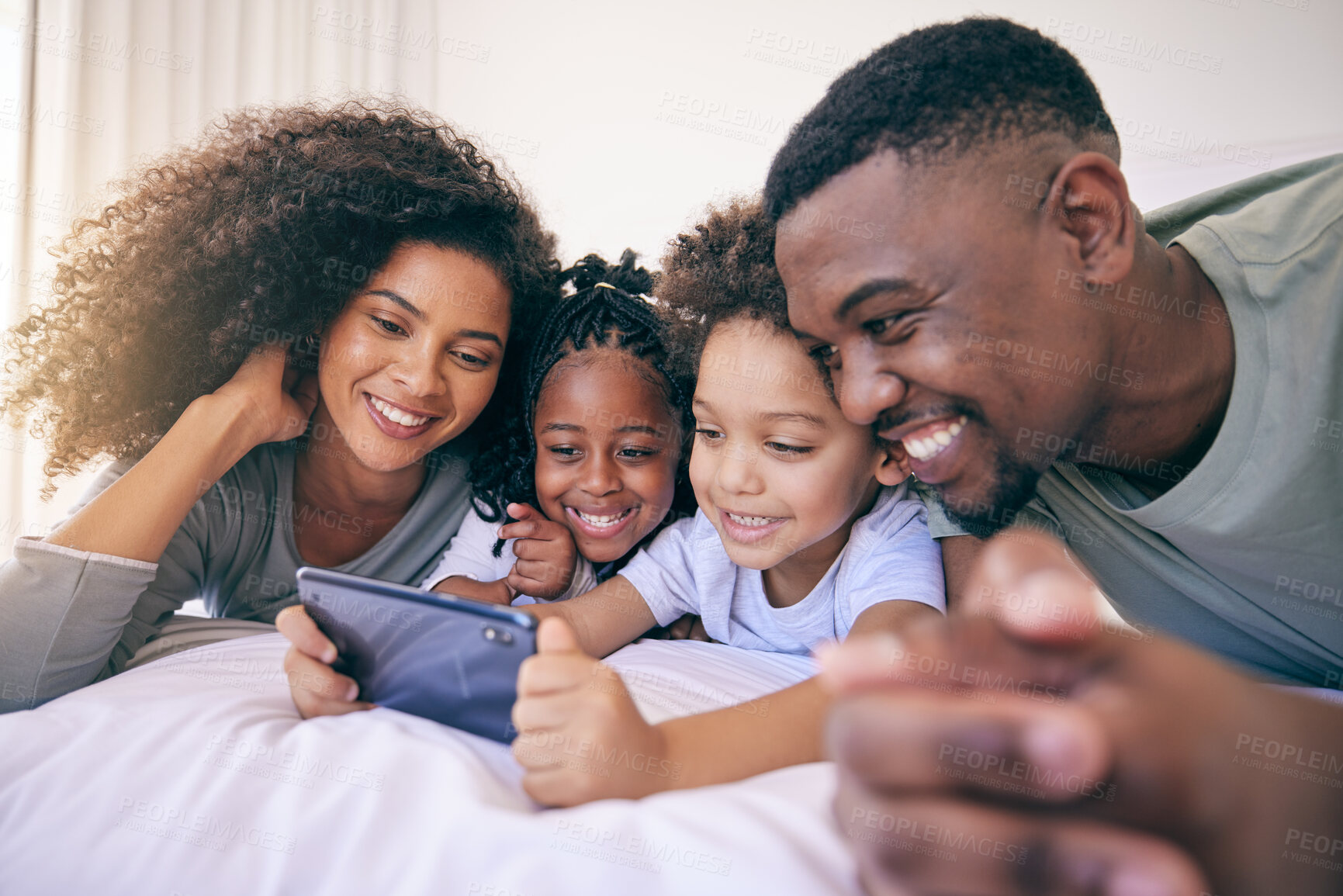 Buy stock photo Phone, bedroom and family watching a video on social media, mobile app or the internet together. Happy, bonding and African children streaming a movie or film on cellphone with their parents at home.