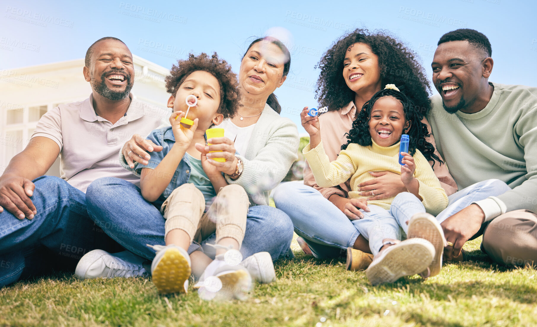 Buy stock photo Family, happiness outdoor and relax on lawn, kids blowing bubbles together with grandparents and parents. Happy people, summer and sitting on grass, love and care, bonding with generations and smile