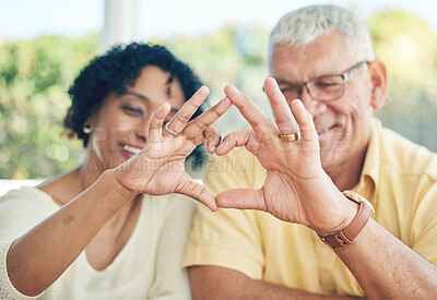 Buy stock photo Senior couple, hands and heart emoji for love, relationship or trust and care in marriage at home. Happy elderly man and woman putting hand together in hearty shape sign, symbol or gesture in romance