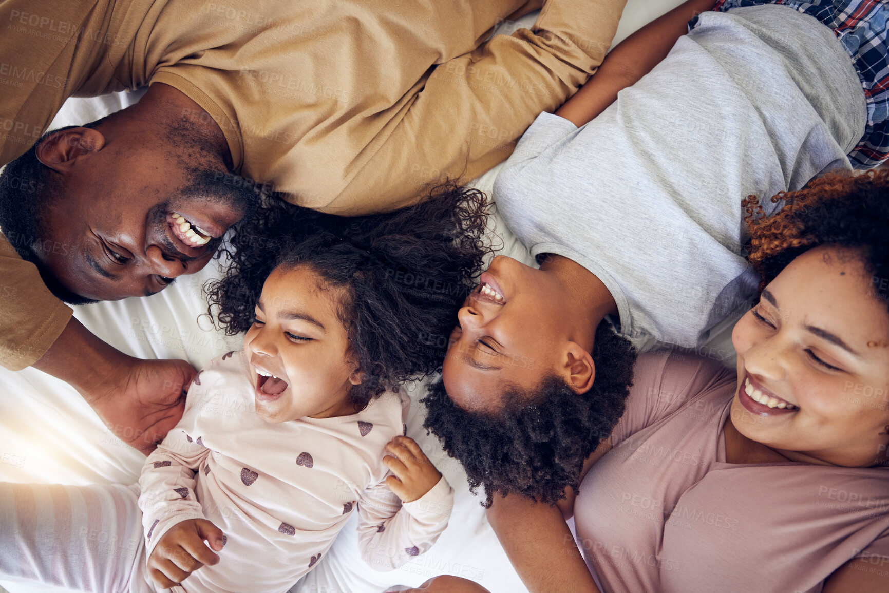 Buy stock photo Happy, above and family laughing in bed, smile and bonding while resting in their home. Top view, smile and children waking up with mother and father in a bedroom, playful and having fun 