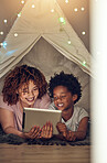 Tablet, black family and mother with kid in tent at night watching movie, video and having fun in home. Technology, love and smile of happy mixed race mom bonding with boy child while streaming film.