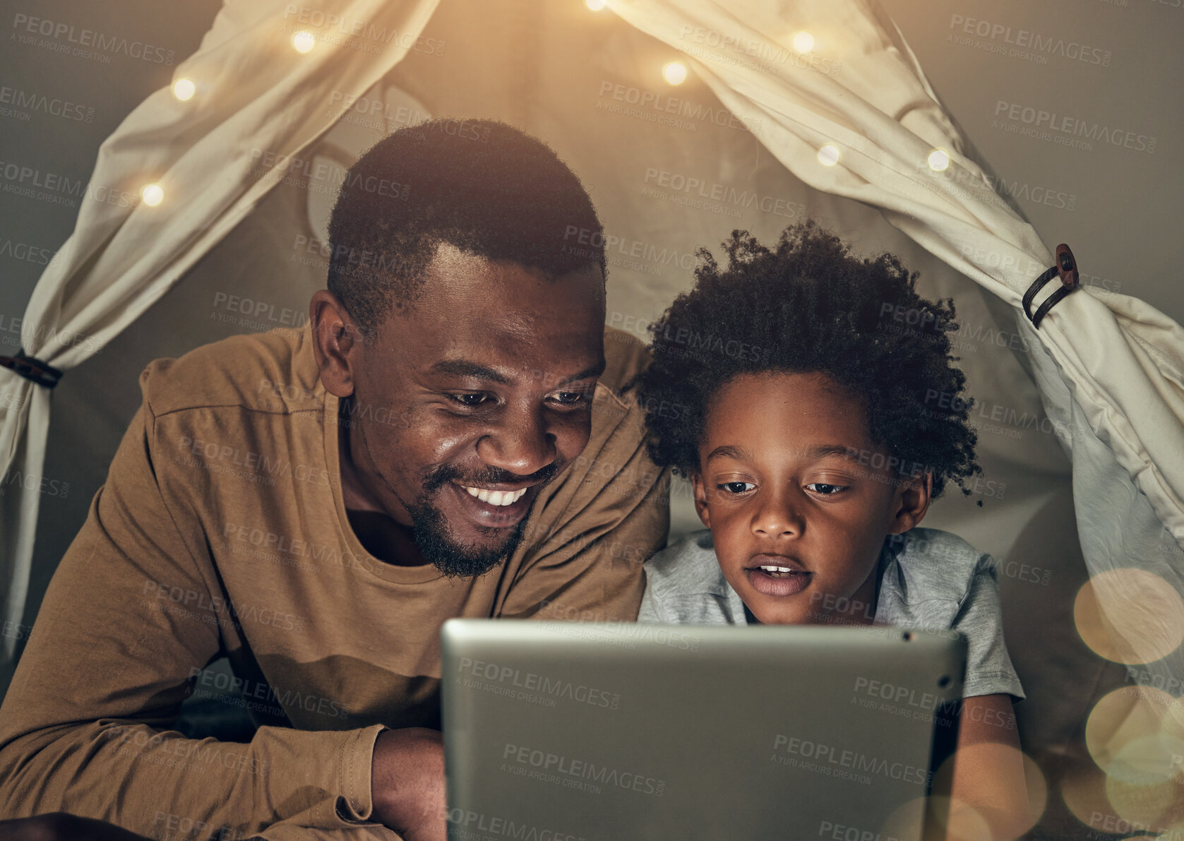 Buy stock photo Black family, tablet and father with kid in tent at night watching movie, video and having fun in home. Technology, bokeh and smile of happy dad bonding with boy child while streaming film in house.