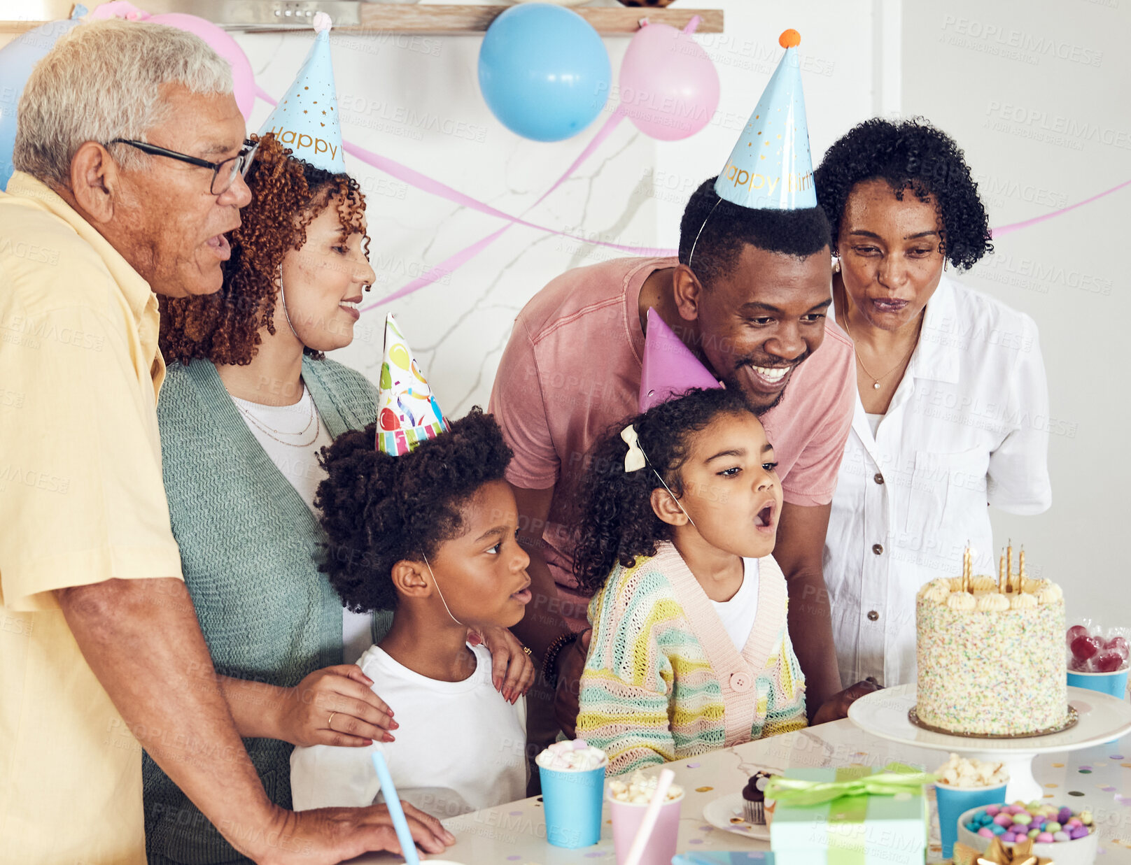 Buy stock photo Birthday, cake and a girl blowing out candles while celebrating with her black family in their home. Kids, party or celebration with parents, grandparents and children bonding together in a house