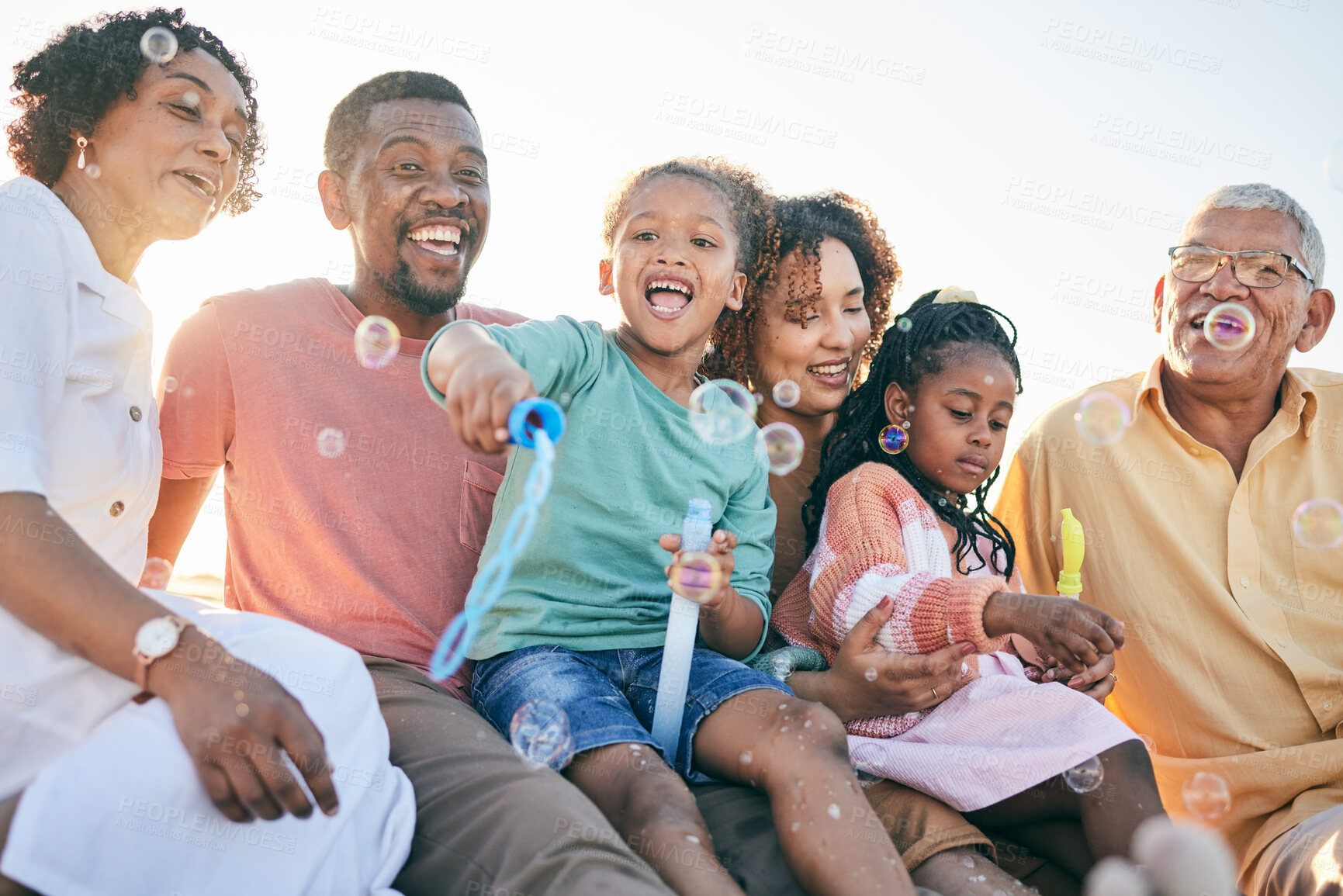 Buy stock photo Relax, happy and bubbles with black family in outdoors for bonding, summer break and generations. Happiness, playful and grandparents with parents and children for free time, weekend or youth