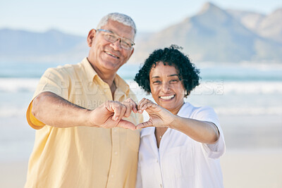 Buy stock photo Hands, heart and a senior couple on the beach together during summer for love, romance or weekend getaway. Portrait, travel or emoji with a mature man and woman bonding outdoor on sand by the coast