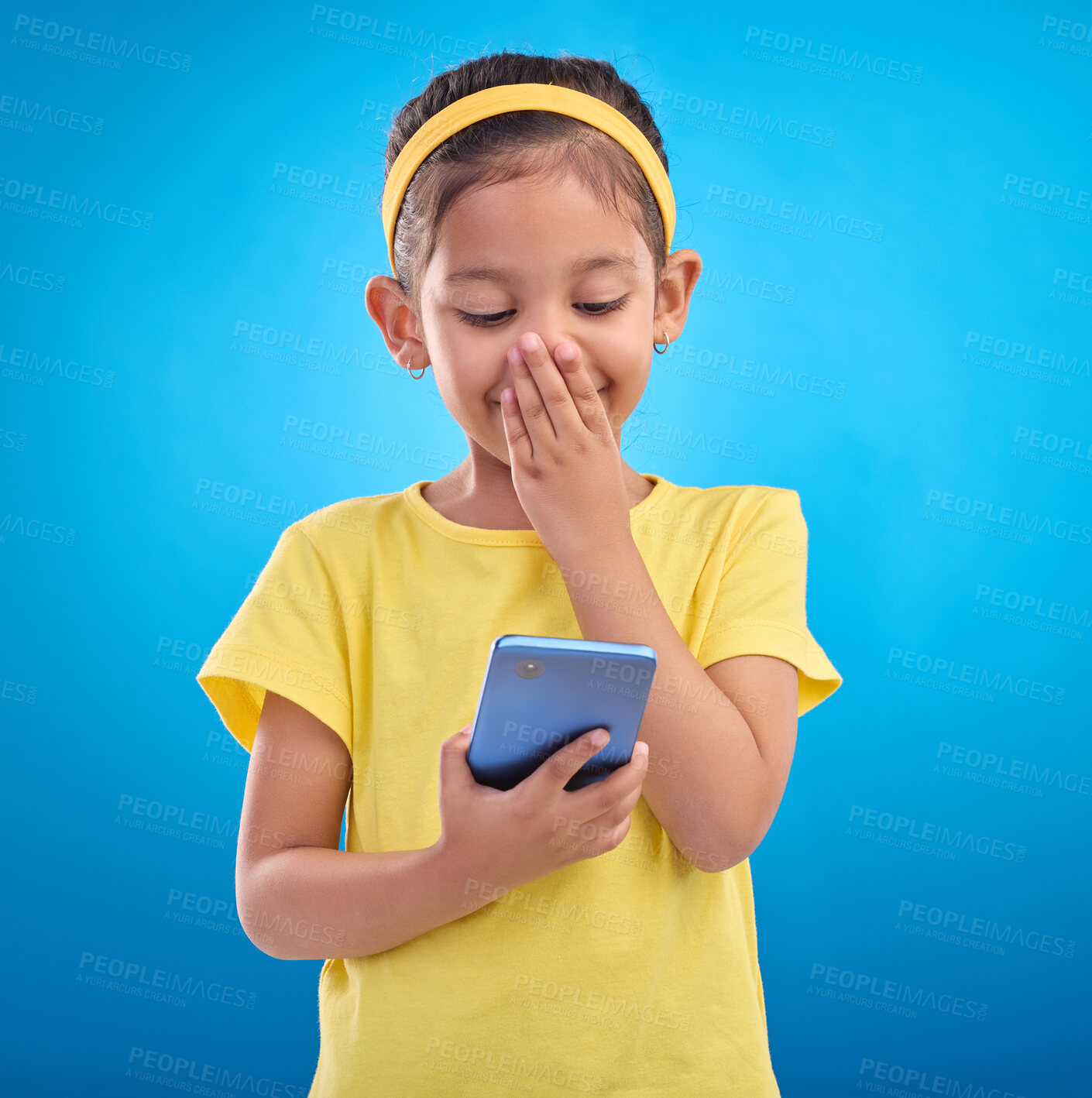 Buy stock photo Phone, smile and child laugh on blue background for social media, funny video and internet meme in studio. Technology, communication mockup and happy girl with humor, joke and online on smartphone