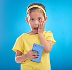 Phone, shock and portrait of child on blue background with wow, omg and surprise expression in studio. Technology, childhood and face of girl shocked for news, announcement or message on smartphone
