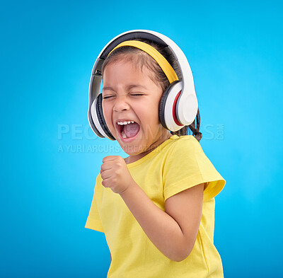 Buy stock photo Music, headphones and singing with girl in studio for streaming, mobile radio and audio. Technology, media and youth with child listening isolated on blue background for natural, happy and songs