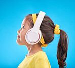 Music, headphones and listening with girl in studio for streaming, mobile radio and audio. Technology, media and youth with profile of child isolated on blue background for natural, happy and songs