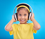 Music, headphones and listening with portrait of girl in studio for streaming, mobile radio and audio. Technology, media and youth with child isolated on blue background for natural, happy and songs