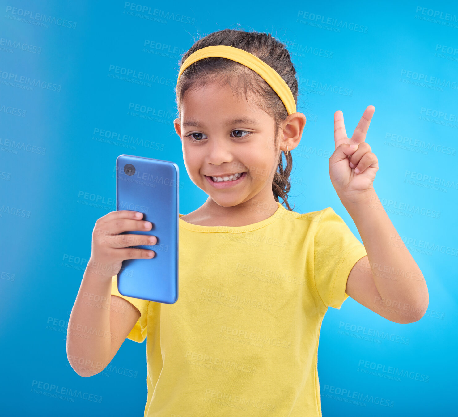 Buy stock photo Phone, girl kid and peace sign selfie in studio isolated on a blue background. Technology, v hand emoji and smile of child with mobile smartphone to take pictures for happy memory or social media.