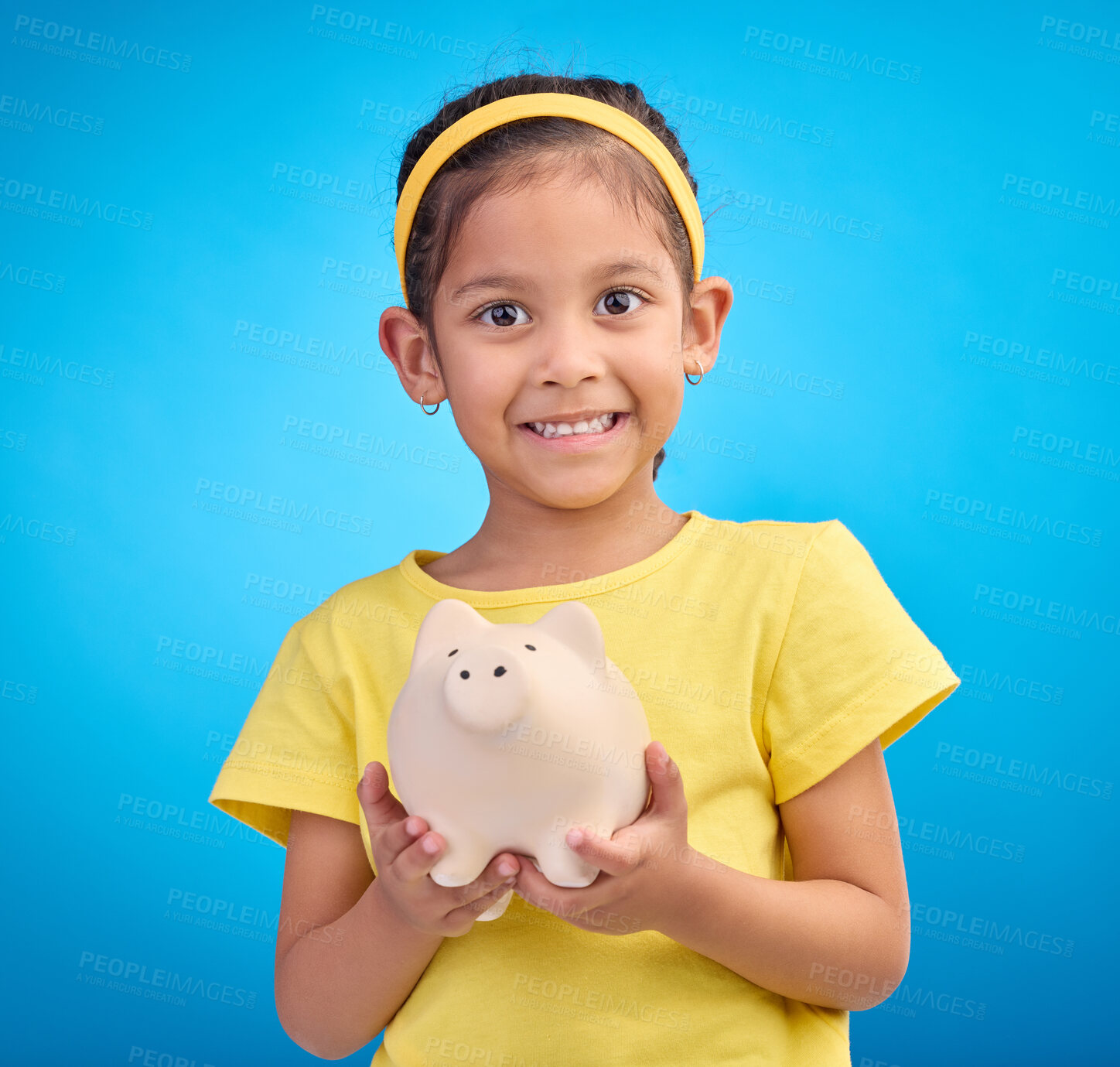 Buy stock photo Face portrait, piggy bank and girl child in studio isolated on a blue background. Happy, smile and kid with cash box, savings or financial, investment or learning budget, finance growth or money.