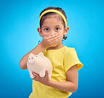 Piggy bank, shocked or surprised child in portrait isolated on blue background savings mistake or investment risk. Wow face of girl kid and saving jar or container for finance or money fear in studio