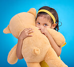 Portrait, hug and child in studio with teddy bear, sweet and innocent on gradient blue background. Face, embracing and child with teddy. hiding and shy, sweet and play while hugging on isolated space