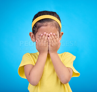 Cover eyes, hands on face and child on blue background for shy, mistake expression and sad in studio. Emotion reaction, childhood and young girl isolated for hide and seek, surprise and blind emoji