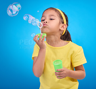Buy stock photo Children, blue background and a girl blowing bubbles in studio for fun or child development of motor skills. Kids, game or soap and a cute or adorable female child playing with a bubble wand 