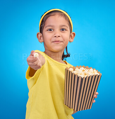 Buy stock photo Popcorn, offer and smile with portrait of girl and giving snack to you for food, cinema and relax. Friendly, movie and film with child eating for streaming, subscription and tv on blue background