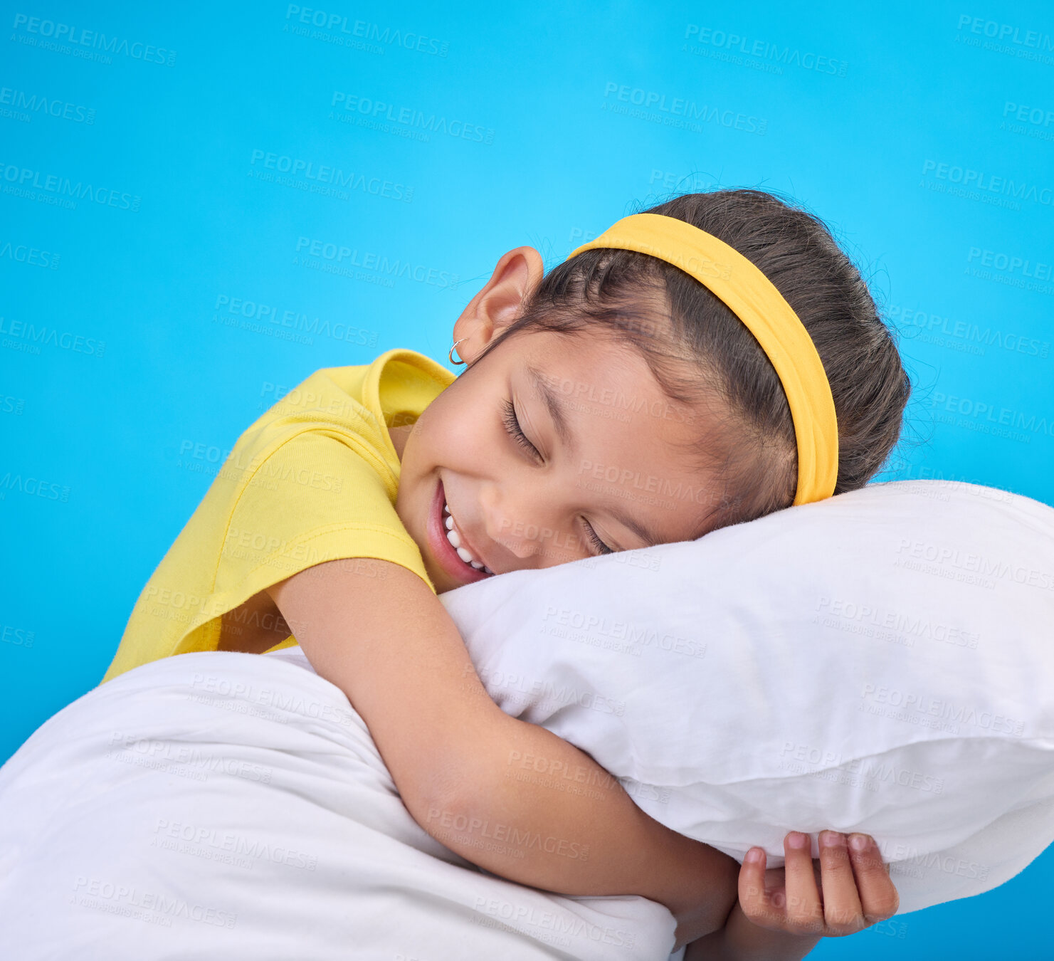 Buy stock photo Young girl smile, pillow and sleep in a studio feeling tired, fatigue and ready for dreaming. Isolated, blue background and happy little child with pillows and closed eyes for sleeping, rest and nap 