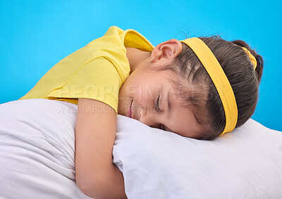 Calm young girl, pillow and sleep in a studio feeling tired, fatigue and ready for dreaming. Isolated, blue background and happy little child with pillows and closed eyes for sleeping, rest and nap