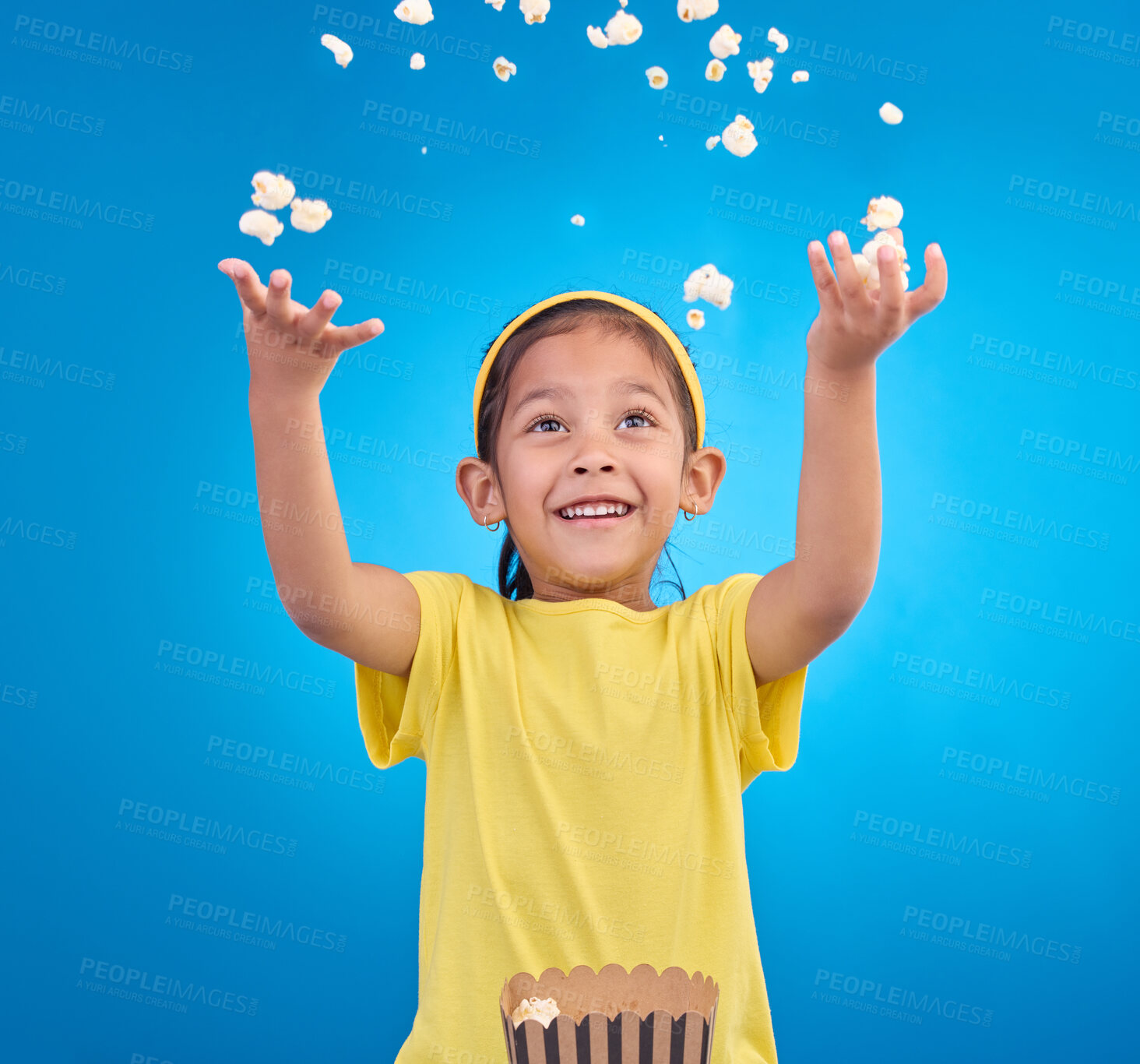 Buy stock photo Food, happy and child throw popcorn on blue background for entertainment, movies and cinema mockup. Comic, smile and excited young girl with sweet snack in studio for party, celebration and eating