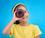 Donut, eye and smile with portrait of girl in studio for junk food, sugar and happiness. Snack, cake and cute with face of child and dessert for cute, positive and chocolate on blue background