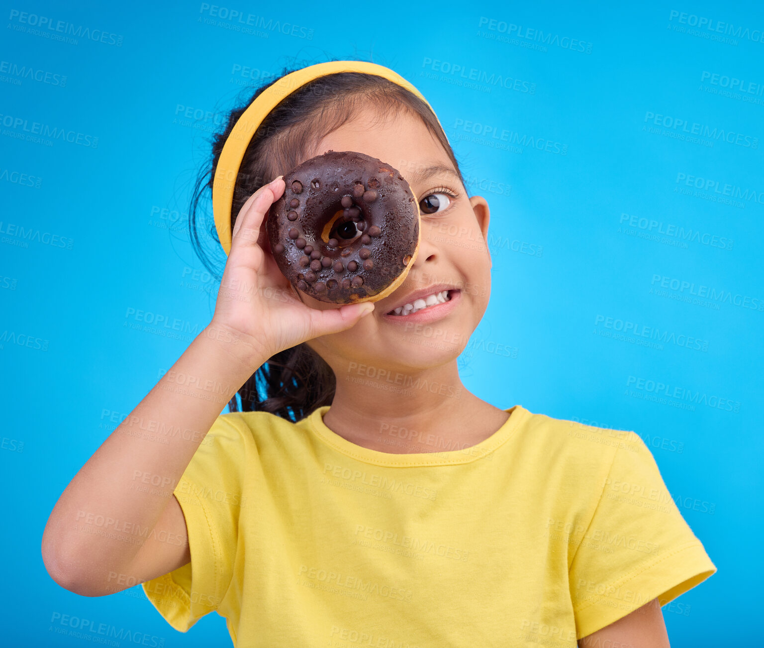 Buy stock photo Donut, eye and smile with portrait of girl in studio for junk food, sugar and happiness. Snack, cake and cute with face of child and dessert for cute, positive and chocolate on blue background
