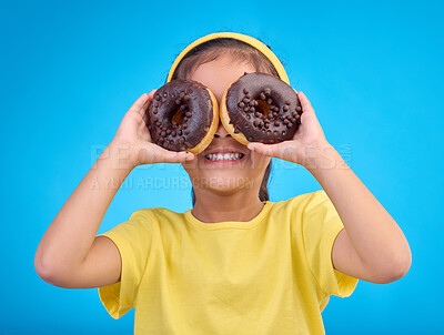 Buy stock photo Donut, eyes and covering face of playful cute girl with food isolated against a studio blue background with a smile. Adorable, happy and young child or kid excited for sweet sugar doughnuts