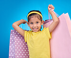 Girl, shopping portrait and gift bags from birthday party, event or celebration with a present in studio. Shop sale, bag and little child with presents with isolated and blue background with a kid