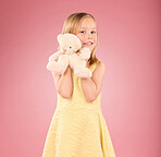Teddy bear, girl and portrait with a soft toy with happiness and love for toys in a studio. Isolated, pink background and a young female child feeling happy, joy and cheerful with stuffed friend