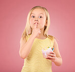 Girl child, finger on lips and cupcake portrait in studio on a pink background for hush and silence. Face of female kid model with cake, secret and sweet snack in hand isolated on color and space