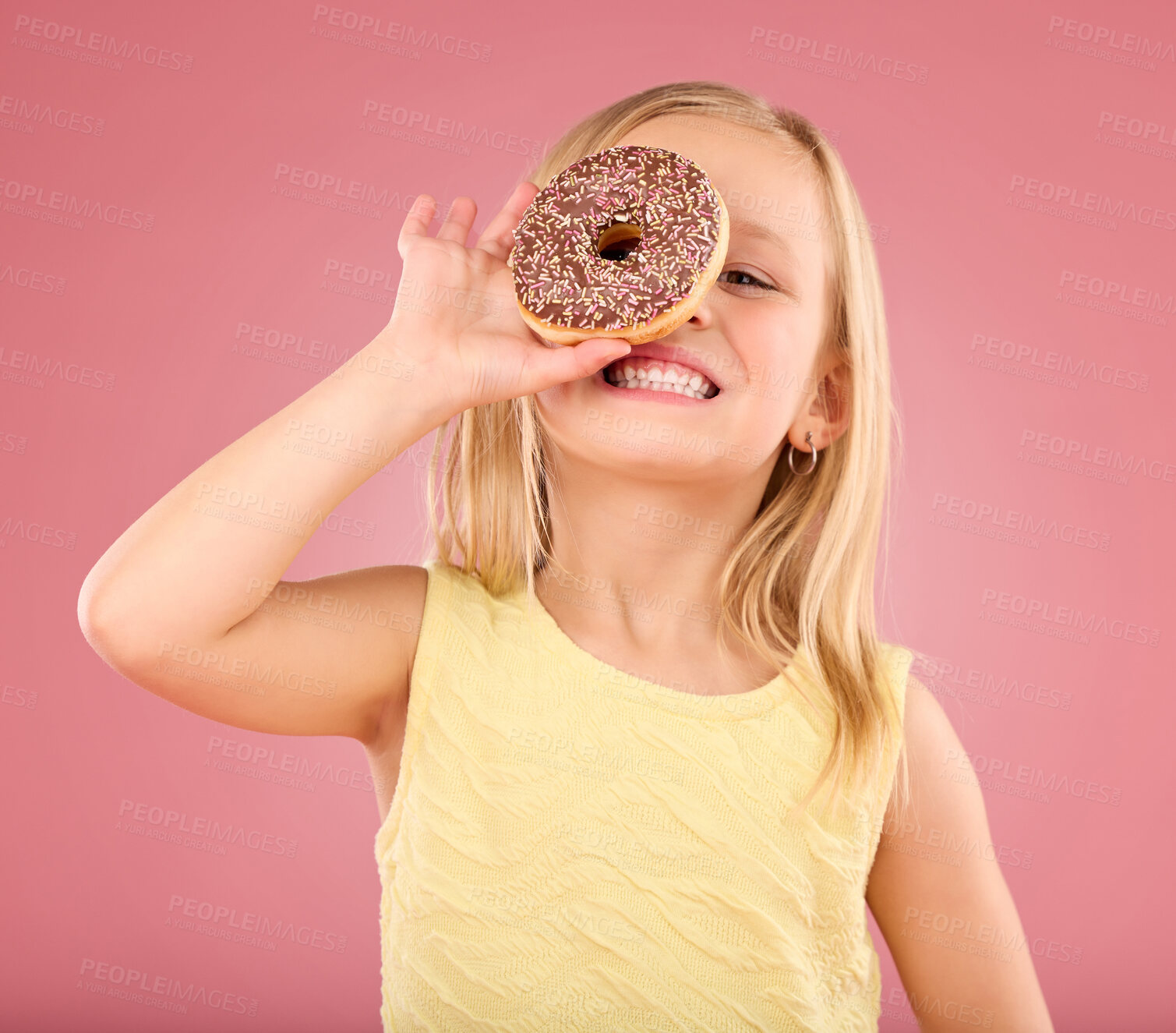 Buy stock photo Child, donut and smile portrait in studio on a pink background while happy about sweet snack. Girl kid model with happiness, creativity and chocolate ring over eye in hand isolated on color and space