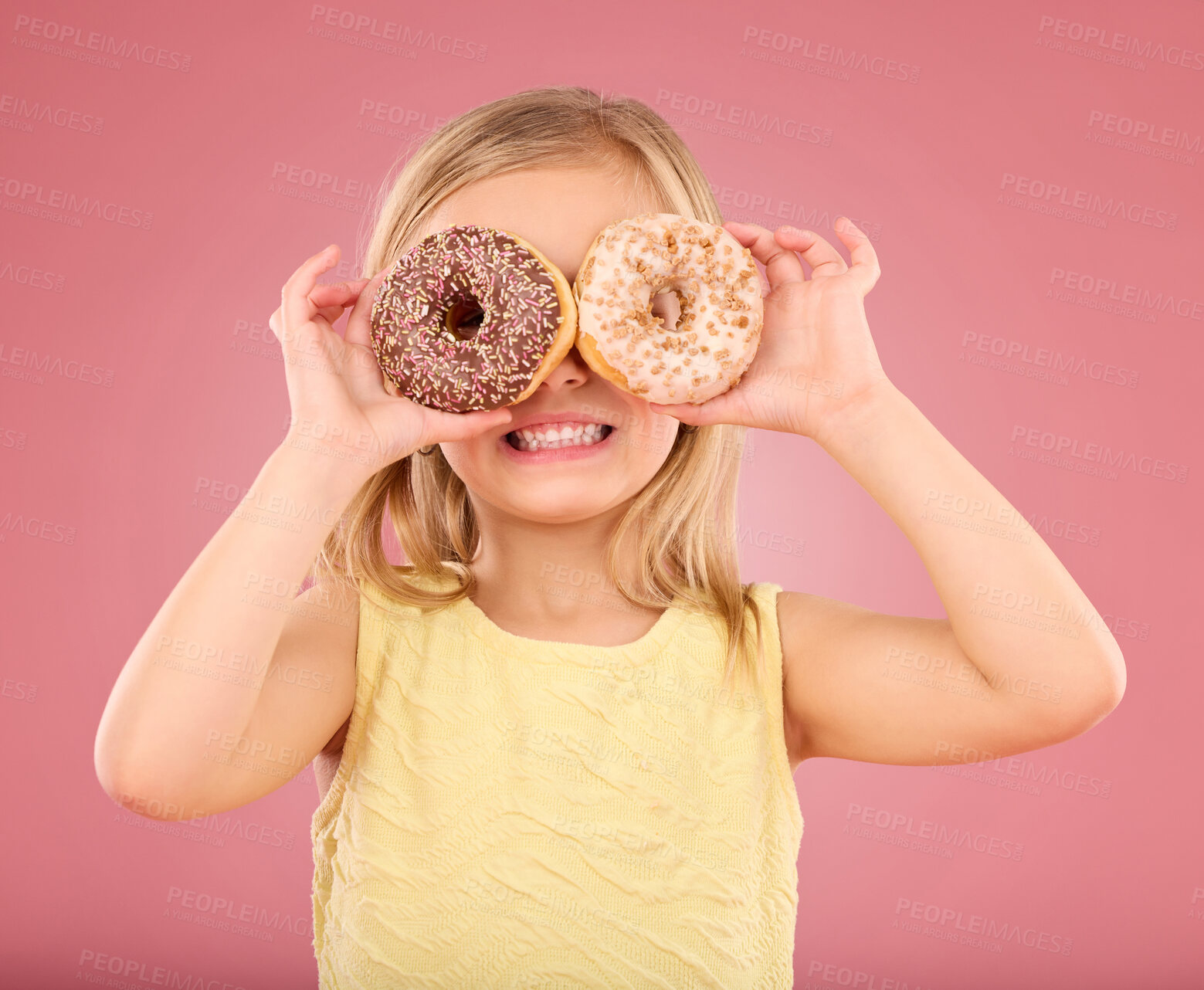 Buy stock photo Child, donut over eyes and smile in studio with sweet snack in hands on a pink background. Girl kid model with happiness, creativity and comic face holding food in hand isolated on color and space