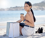 Woman with shopping bag, portrait and relax on beach after retail therapy, fashion and rest with coffee. Female outdoor, latte drink and smile, happy with discount or sale with freedom and travel