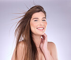 Portrait, hair and wind with a woman in studio on a gray background for haircare or keratin treatment. Shampoo, salon and beauty with an attractive young female model posing in a breeze on a wall