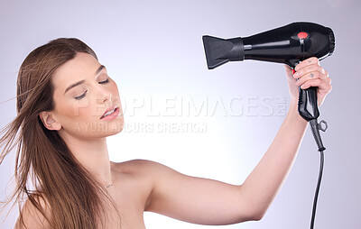 Buy stock photo Beauty, hair dryer and a woman blowing her hairstyle in studio on a gray background for grooming or style. Salon, cosmetics and appliance with an attractive young female using heat to blowdry