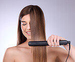 Hair straightener, face and beauty of woman in studio isolated on a gray background. Eyes closed, haircare and happy female model with flat iron product for salon treatment, balayage and hairstyle.