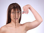 Beauty, salon and woman cutting her hair in studio on a gray background for style or care. Grooming, shampoo and haircut with an attractive young female trimming her hairstyle for haircare