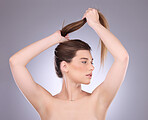 Thinking, beauty and hair care of a woman in studio isolated on a gray background. Cosmetics, growth and female model with salon treatment for healthy keratin, balayage texture or long hairstyle pull