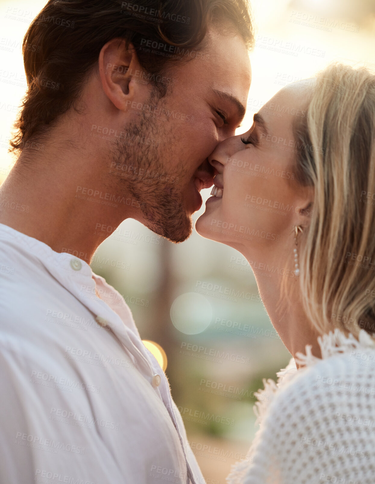 Buy stock photo Love, sunset and kiss with couple in nature for romance, bonding and affectionate together. Close, happiness and embrace with man and woman hugging on date for smile, anniversary and summer break
