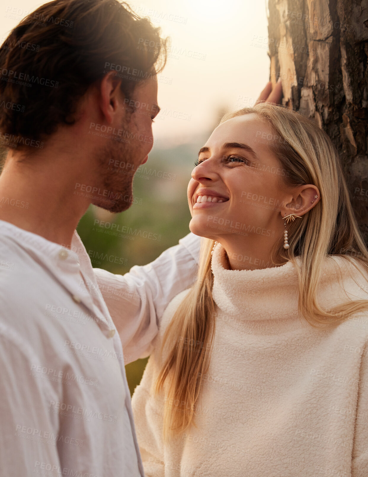 Buy stock photo Happy, love and couple by tree in nature at sunset for romance, bonding and quality time together. Romantic, dating and man and girl show affection on holiday, honeymoon vacation and relax on weekend