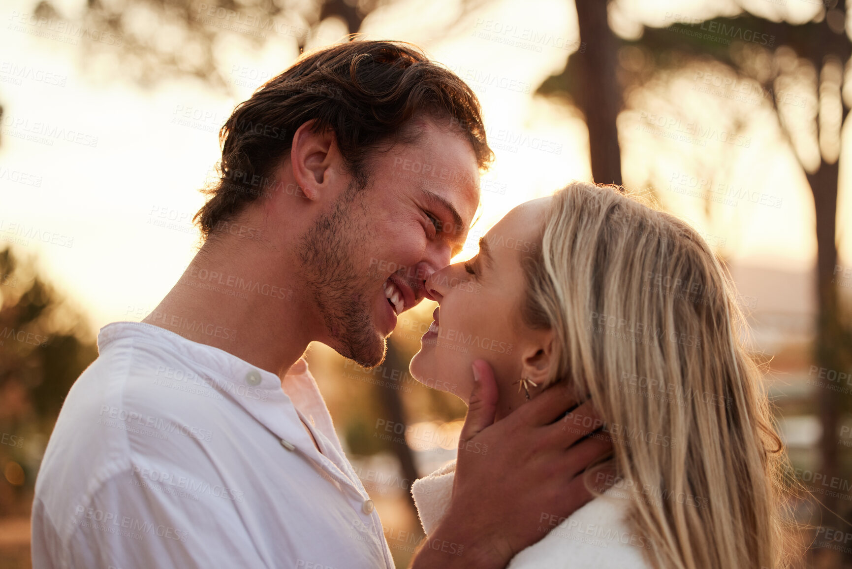 Buy stock photo Love, happy and kiss with couple in nature for romance, bonding and affectionate together. Close, happiness and embrace with man and woman hugging on date for sunset, anniversary and summer break