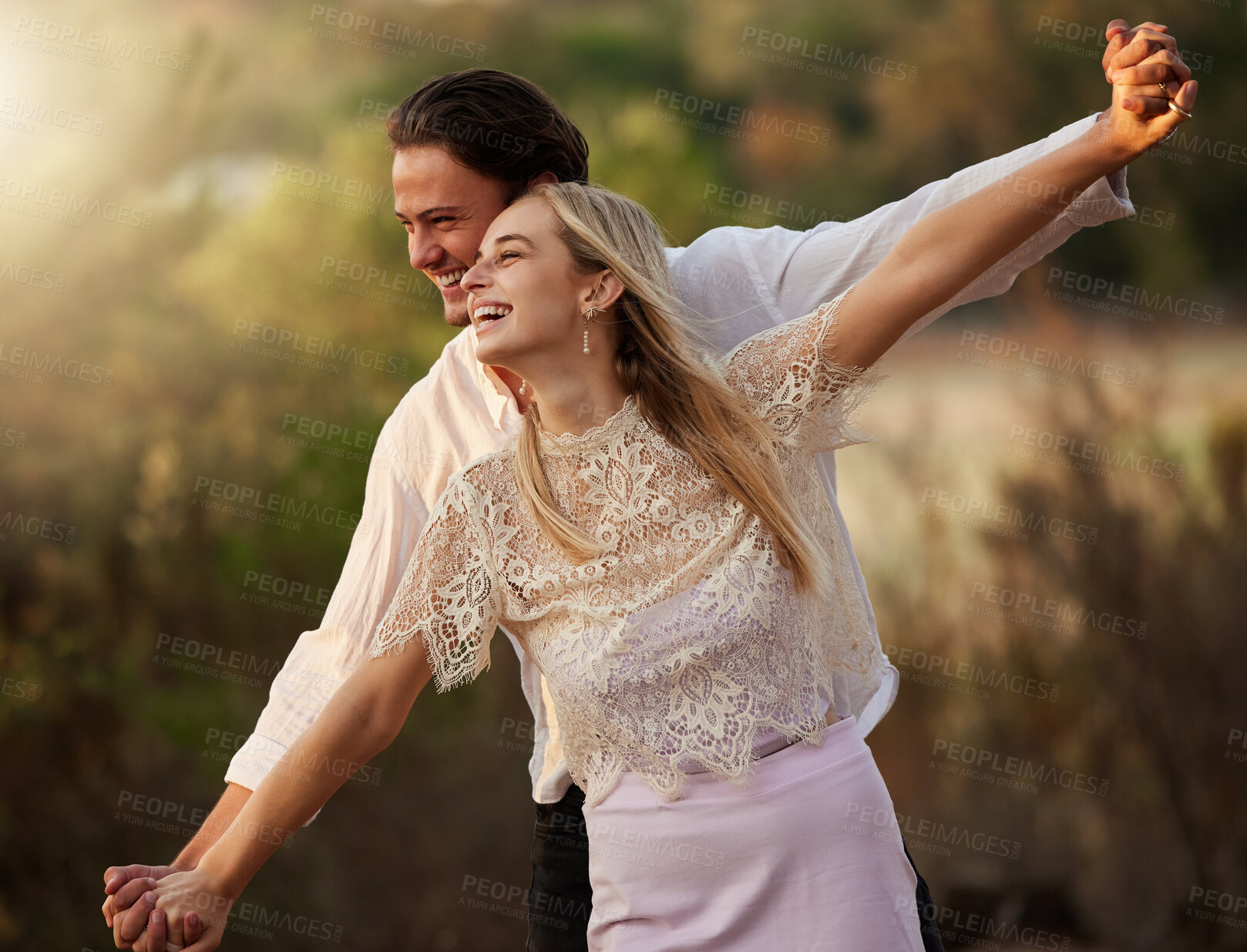 Buy stock photo Nature, romance and couple with playful freedom on romantic honeymoon or summer date. Love, woman and man holding hands, flying gesture and happy smile bonding together on weekend at sunset in forest