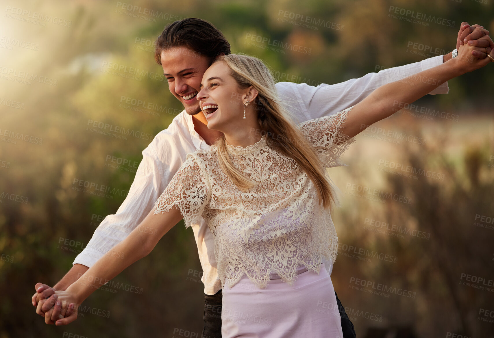 Buy stock photo Happy, love and couple laugh in nature at sunset for romance, bonding and quality time together. Summer, dating and man and woman holding hands on holiday, honeymoon vacation and relax on weekend