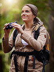 Binocular, forest and hiking happy woman in travel journey, jungle adventure or nature explore with backpack gear. Fitness hiker or camper person trekking in woods and search or birdwatching outdoor
